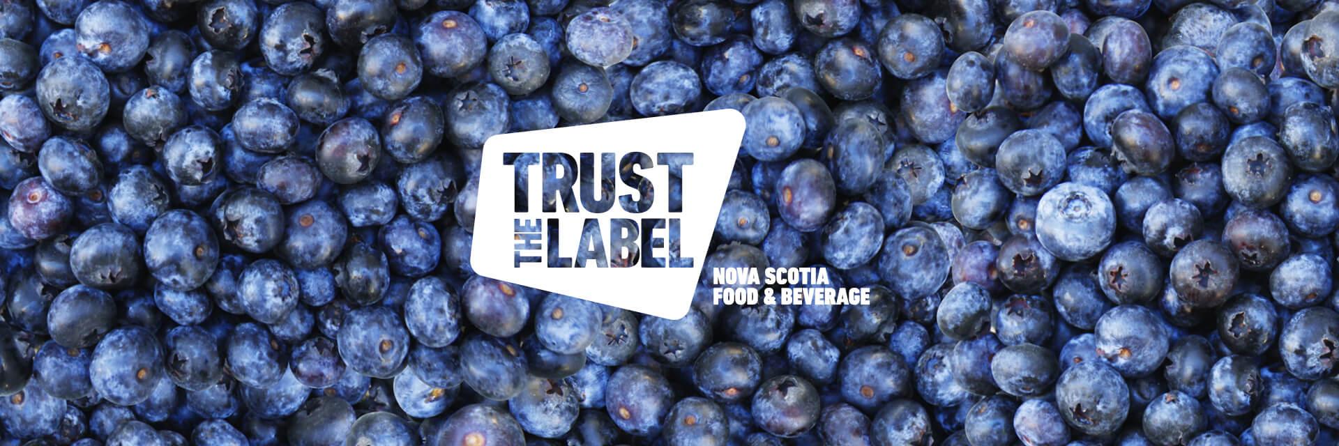 A 'Trust the Label' Nova Scotia Food and Beverage logo overlaid on a photo of blueberries.