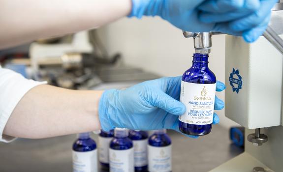 Person filling hand sanitizer product bottle in lab